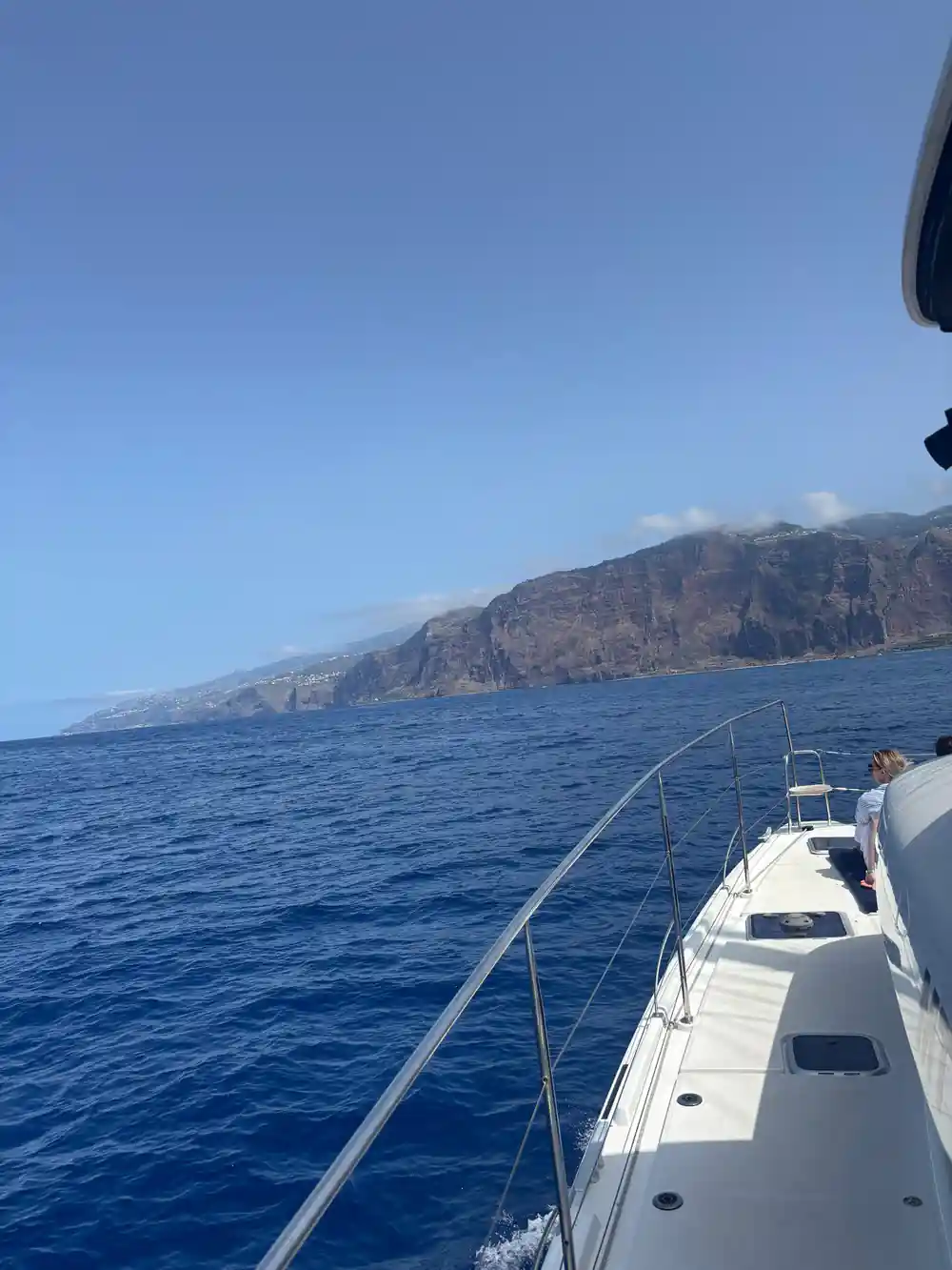 The bow of the catamaran pointing toward a headland