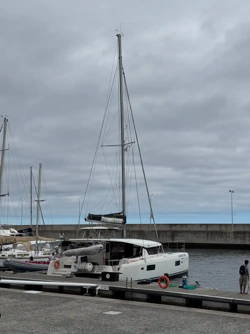 Catamarans moored along the marina pontoon under grey sky