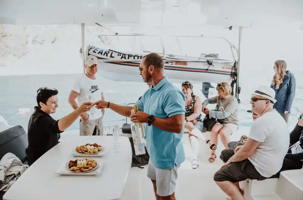 Crew serving drinks and snacks to guests on deck