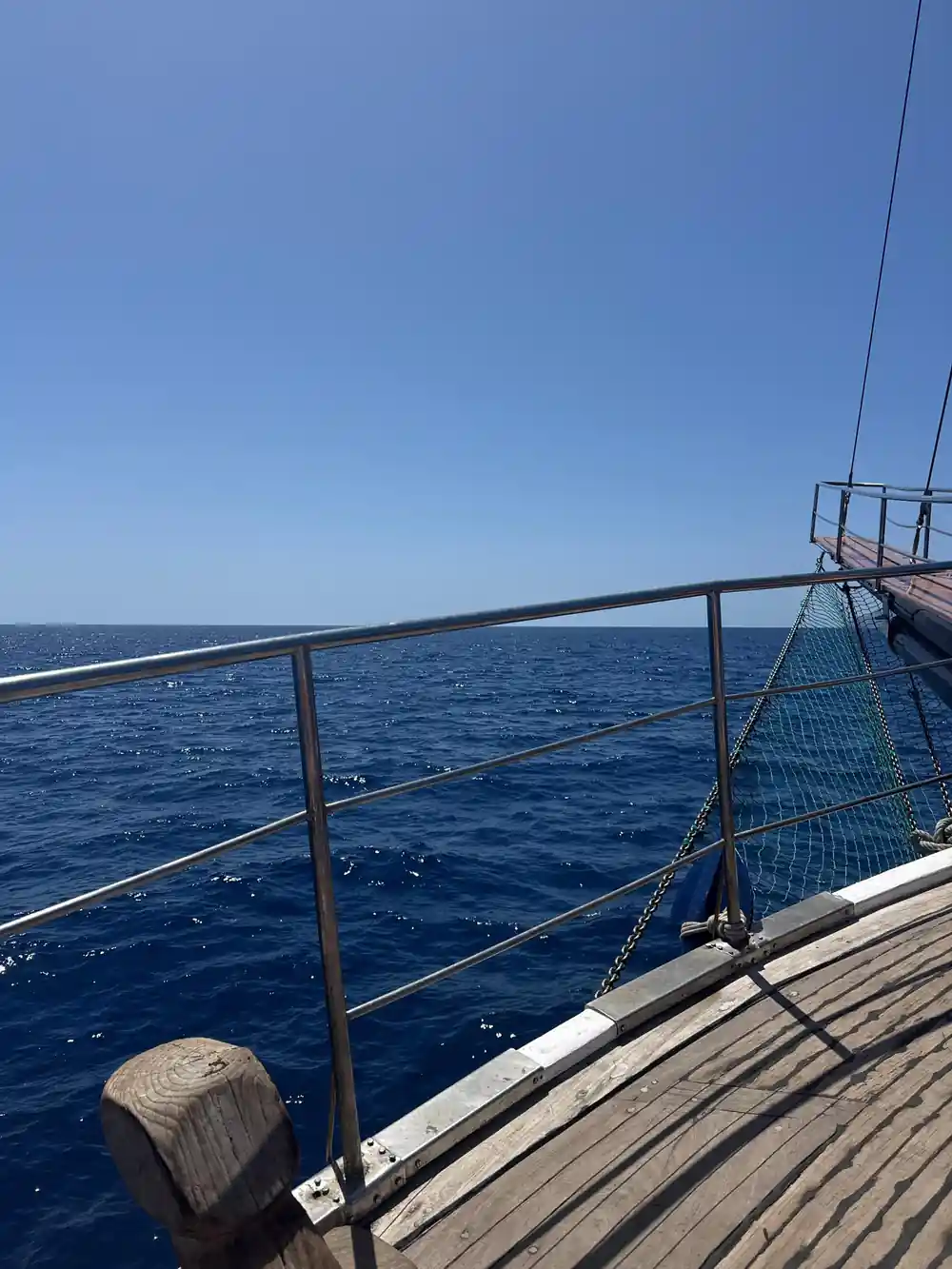 The foredeck nets and rail against a clear blue sky