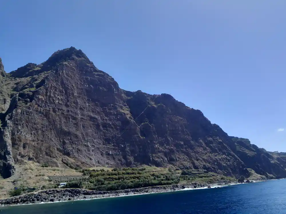 A huge cliff face rising sheer from the sea with terraces below