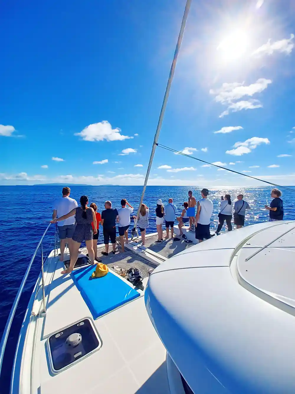 Passengers lining the foredeck rail on a bright blue day