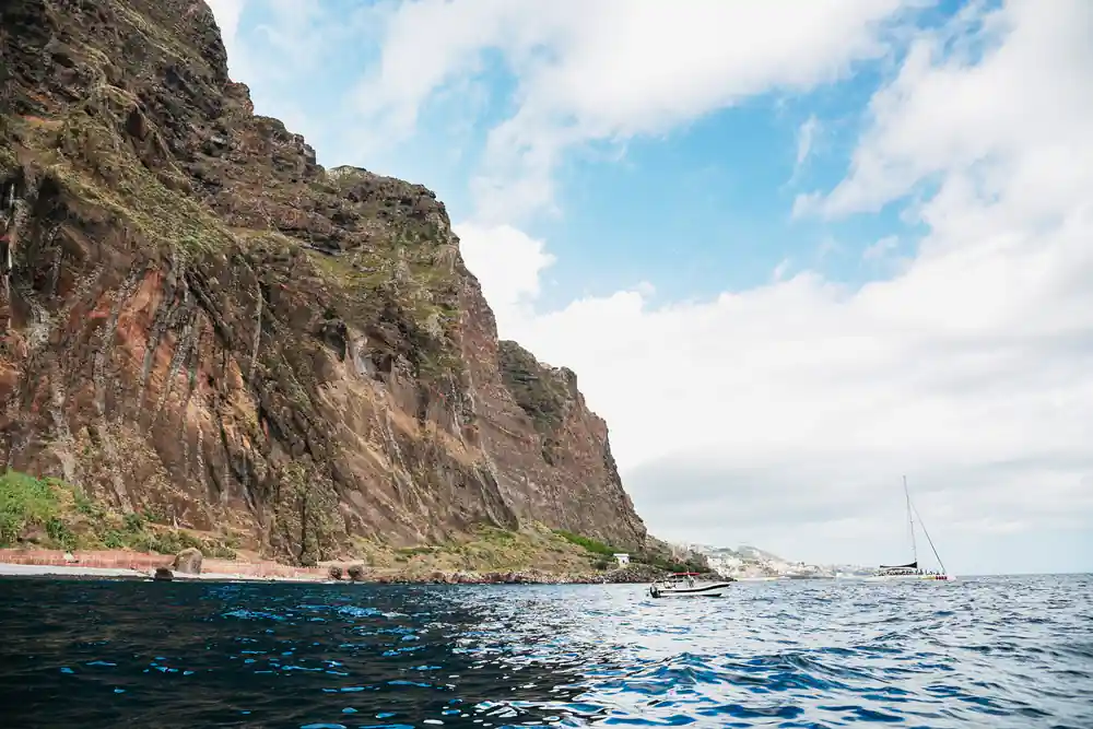 A tall headland dropping straight into the sea under blue sky